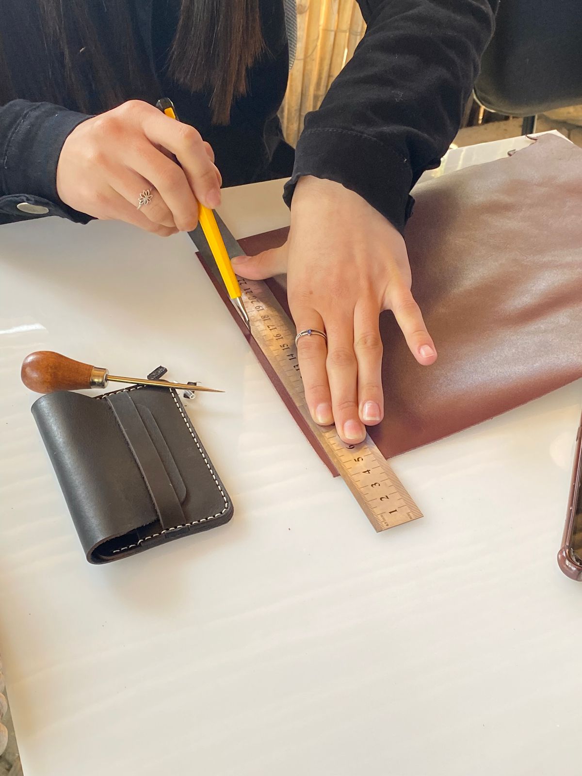 Artesã trabalhando com couro, medindo e cortando material